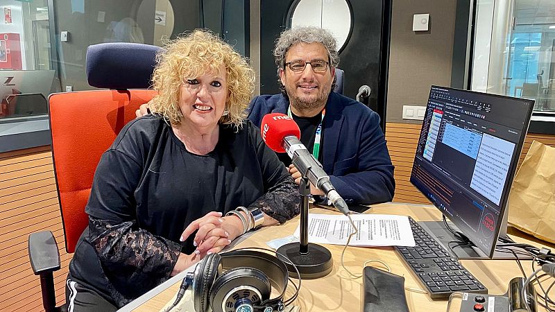 Dos personas sonrientes en un estudio de radio profesional, rodeados de micr�fonos, auriculares y paneles ac�sticos.