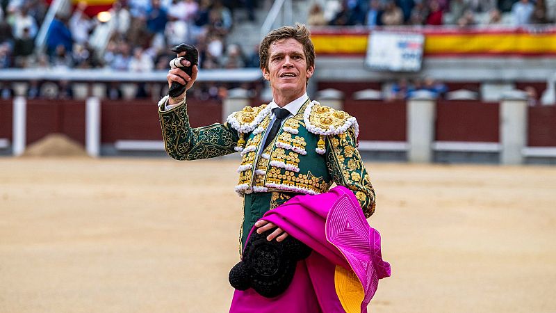 El matador Borja Jiménez celebra una vuelta al ruedo en Las Ventas vistiendo un traje verde botella y oro, mostrando una oreja de toro con el brazo alzado.