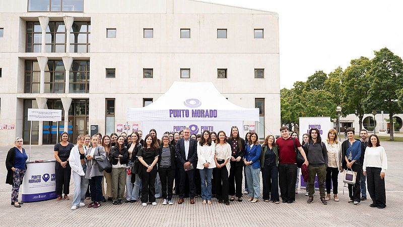 Un grupo de personas posa frente a la carpa del Punto Morado en el campus universitario.