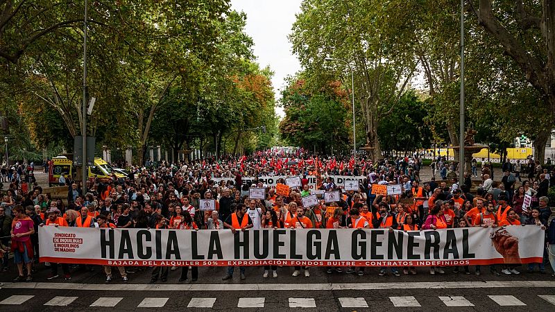 Multitudinaria manifestaci�n por la vivienda en una avenida arbolada, con personas sosteniendo una gran pancarta blanca con lemas reivindicativos y chalecos reflectantes.
