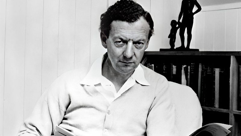 Retrato en blanco y negro del compositor Benjamin Britten sentado, mirando fijamente con expresi�n seria, vistiendo camisa blanca y sosteniendo una partitura.