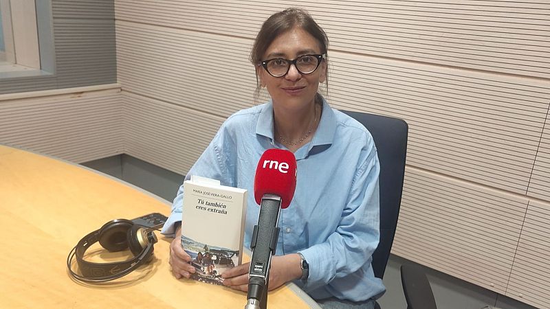La escritora María José Viera-Gallo sostiene su novela en un estudio de radio, frente a un micrófono con el logotipo de RNE.