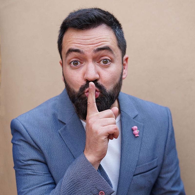 Un hombre con barba oscura y chaqueta azul, con un pin rosa, se lleva el dedo a los labios en se�al de silencio. En la imagen se leen las palabras "tonicano" y "Xavif�rnia".
