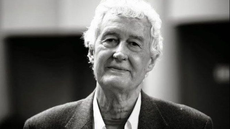 Retrato en blanco y negro de un hombre con abundante cabello blanco y rizado, chaqueta oscura y una expresi�n serena con leve sonrisa.