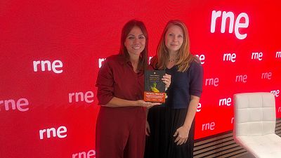 Susana Santaolalla y Tatiana ?�buleac posan sonrientes en un estudio de radio sosteniendo un libro juntas.