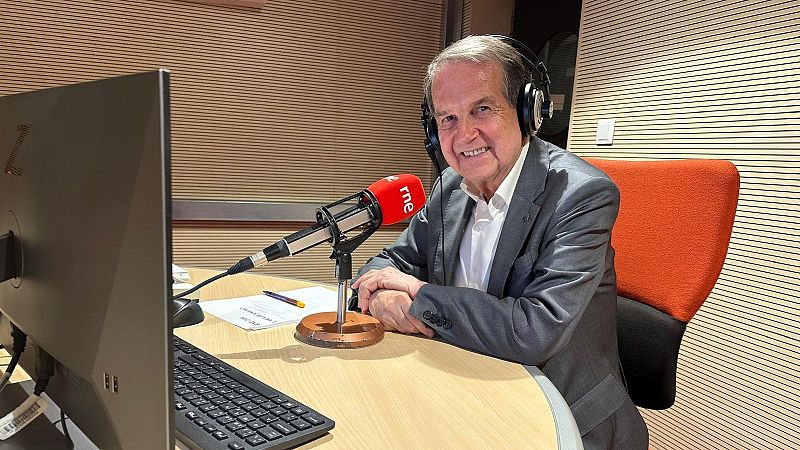 Abel Caballero sonríe sentado ante un micrófono de RNE en un estudio de radio, vistiendo chaqueta gris y auriculares.
