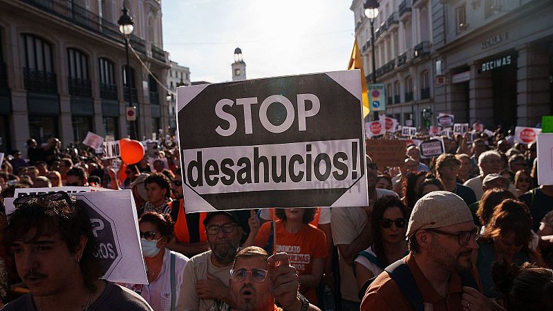 Manifestación por el derecho a la vivienda en Madrid con pancarta «STOP desahucios!» y asistentes con camisetas naranjas.