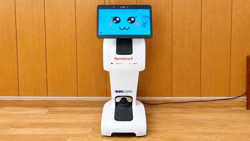 Robot asistencial blanco con pantalla t�ctil que muestra un rostro animado, logotipo de samcare y base con sensor LiDAR.