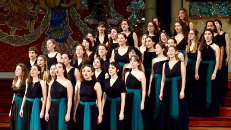 Un grupo de j�venes cantantes act�a en un coro sobre un escenario decorado con mosaicos modernistas.