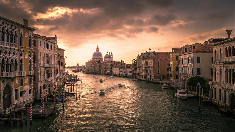 Vista panor�mica del Gran Canal de Venecia al atardecer desde el Puente de la Academia, mostrando la Bas�lica de Santa Maria della Salute y palacios hist�ricos.