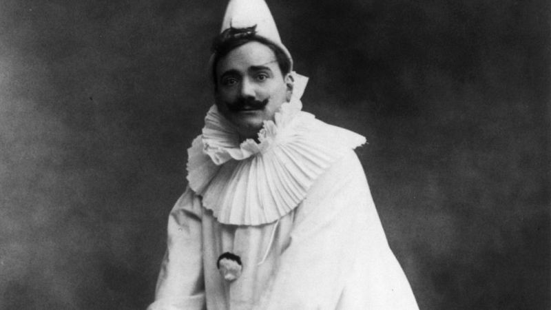 Retrato en blanco y negro del tenor Enrico Caruso caracterizado como payaso tr�gico con traje blanco y gorguera, mostrando expresi�n seria.