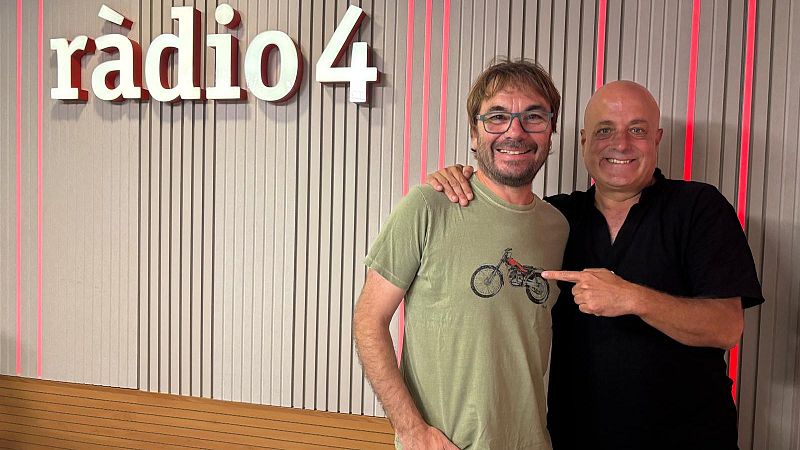 Dos hombres posan sonrientes en un estudio de radio frente a un panel ac�stico, con uno de ellos se�alando la moto estampada en la camiseta del otro.