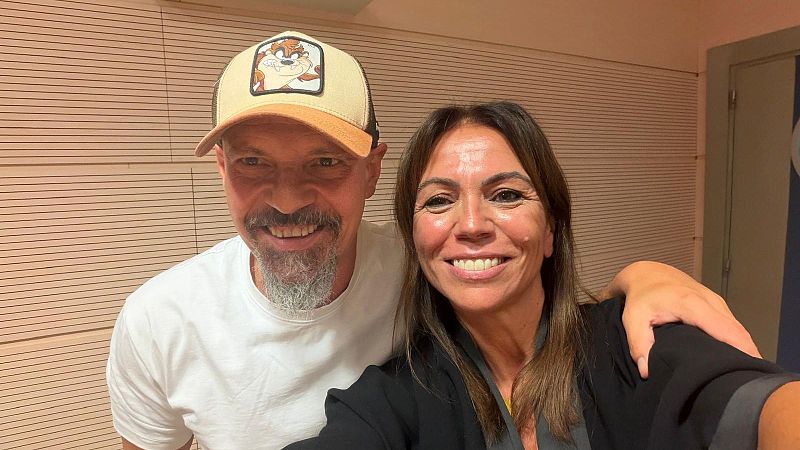 Selfi en un estudio de radio de César Pérez Gellida con camiseta blanca y gorra, y la periodista Susana Santaolalla sonriendo mientras sostiene la cámara.