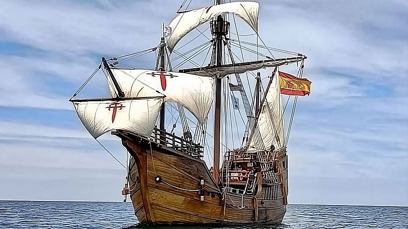 R�plica de un barco hist�rico espa�ol de madera con velas blancas y la Cruz de Santiago navegando en el mar.