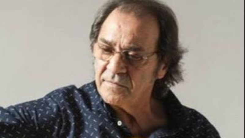 Primer plano del guitarrista flamenco Pepe Habichuela con expresi�n concentrada, gafas finas y camisa oscura sobre fondo claro.