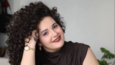 La escritora Inma Rubiales sonr�e a la c�mara en plano medio corto, luciendo melena rizada y prenda marr�n de punto.