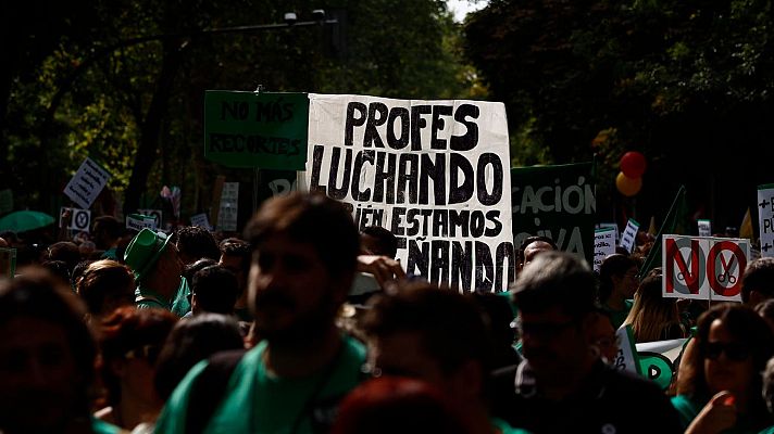 Manifestantes en una protesta educativa portan pancartas con lemas y símbolos contra los recortes, vistiendo prendas de color verde.