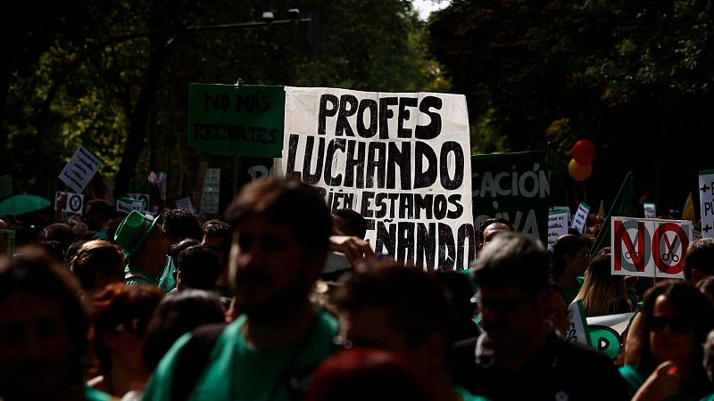 Manifestantes en una protesta educativa portan pancartas con lemas y símbolos contra los recortes, vistiendo prendas de color verde.