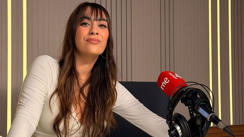Miriam Saint Germain sonr�e en un estudio de radio junto a un micr�fono con antiviento rojo de RNE y R�dio 4.