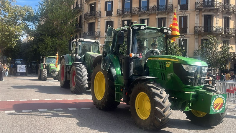 Manifestaci�n de tractores agr�colas avanzando por una calle urbana flanqueada por edificios cl�sicos y espectadores.