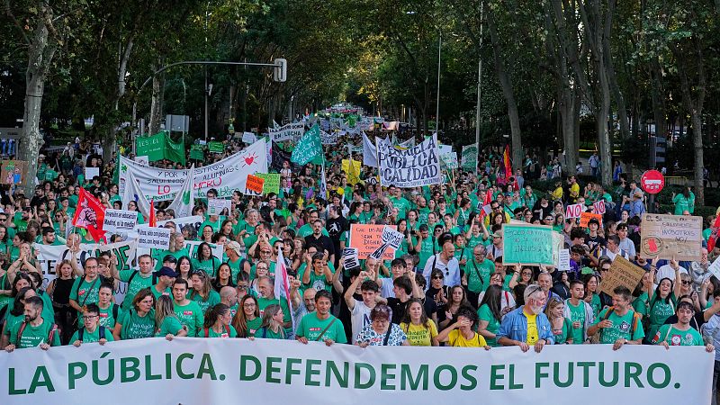 Manifestación multitudinaria en una avenida urbana arbolada donde los asistentes portan una pancarta blanca con la inscripción «LA PÚBLICA. DEFENDEMOS EL FUTURO.» y múltiples carteles reivindicativos.