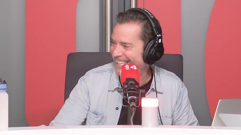 El presentador Vador Llad� sonr�e ampliamente en un estudio de radio, con auriculares y micr�fono de una emisora ante un fondo de paneles ac�sticos.