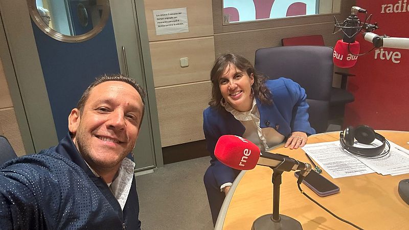 Selfie del bailaor Manuel Liñán y la periodista Olga Baeza sonrientes en un estudio de radio con micrófonos y material de locución.