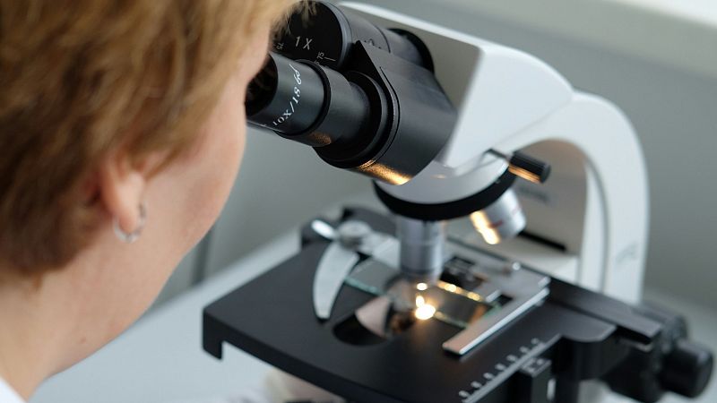 Científica mirando por un microscopio