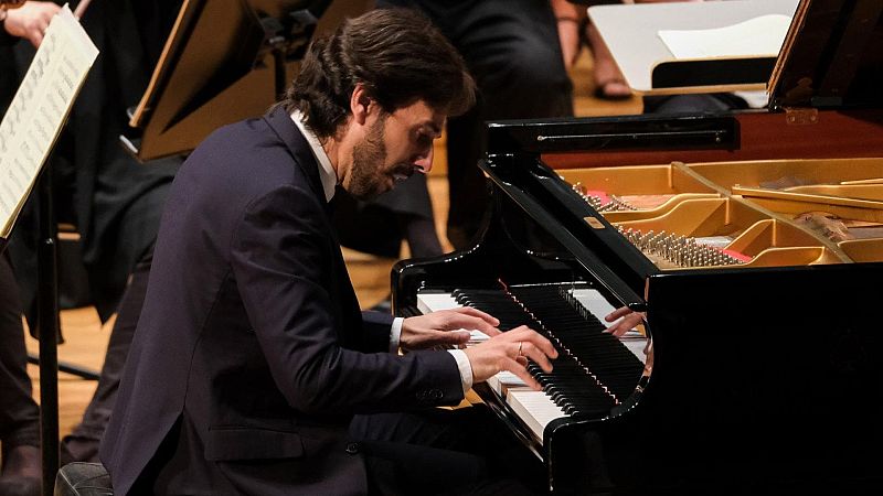 El pianista Iv�n Mart�n toca concentrado un piano de cola negro en un escenario con suelo de madera.