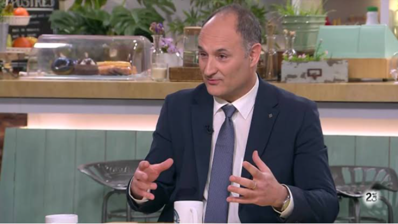Joan Rodr�guez Teruel habla en un plat� con dise�o de cafeter�a, vistiendo traje y haciendo gestos expresivos con las manos.