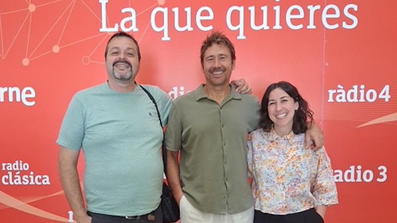 Tres personas posan sonrientes ante un panel corporativo rojo de Radio Nacional de Espa�a, abrazados y con ropa informal de verano.