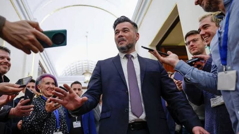 Gabriel Rufi�n atiende a los medios en el Congreso de los Diputados rodeado de reporteros que sostienen tel�fonos y grabadoras.