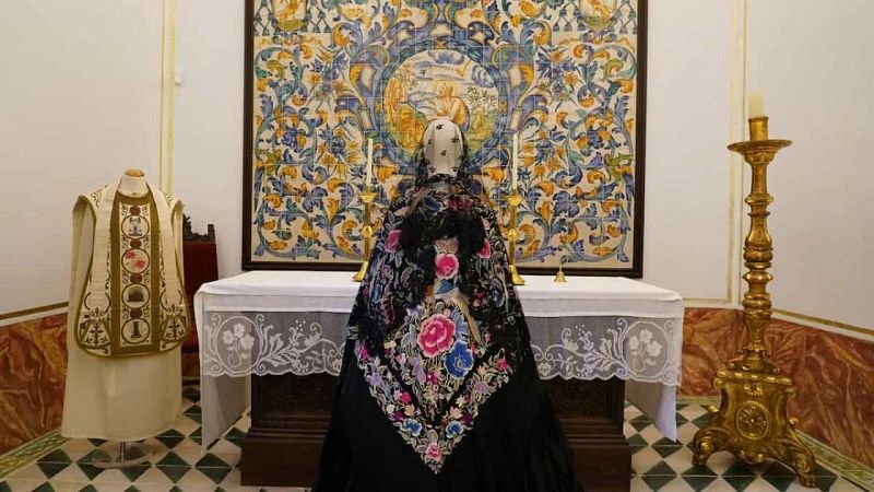 Maniquí de espaldas con mantón de Manila negro bordado de flores ante un altar y retablo de azulejos en la capilla del Museo de la Seda.