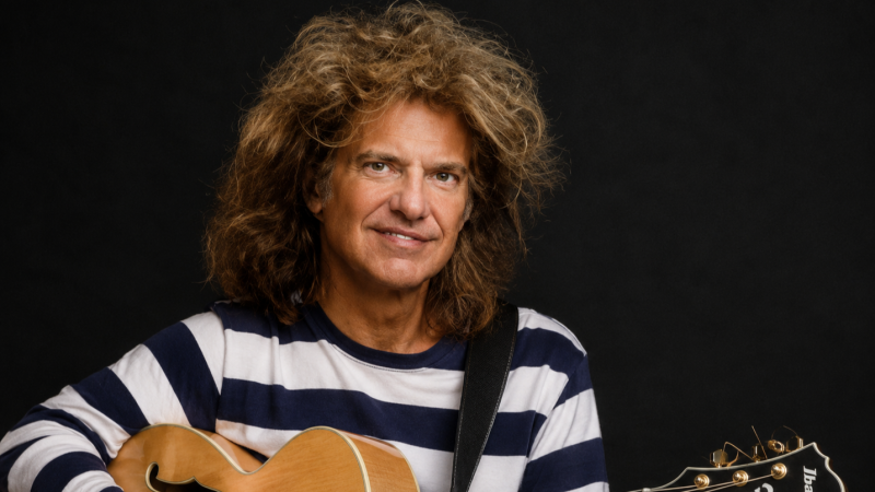 Retrato de estudio del guitarrista Pat Metheny con camiseta de rayas y guitarra el�ctrica de cuerpo hueco.