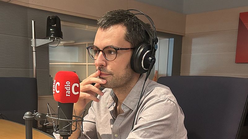 Hombre con gafas y auriculares de estudio reflexivo ante el micr�fono con el logotipo de Radio Cl�sica.