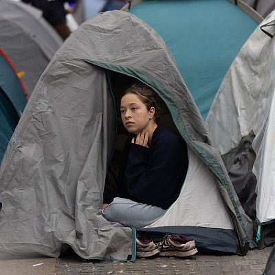 Una joven con expresión seria en una tienda de campaña durante la acampada por la vivienda en la Puerta del Sol en Madrid