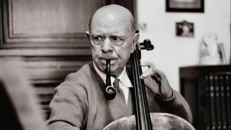 Fotograf�a en blanco y negro del violonchelista Pau Casals tocando su instrumento con una pipa en los labios.