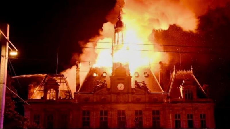Imagen nocturna de un edificio hist�rico con la torre campanario y el tejado en llamas, mientras un chorro de agua intenta apagar el incendio.