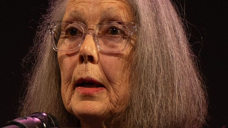 Primer plano de la escritora Anne Carson con gafas de montura transparente y expresi�n reflexiva durante una intervenci�n.