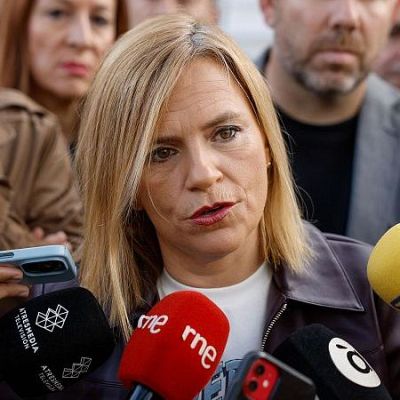 Cristina Ibarrola realiza declaraciones ante numerosos micrófonos de prensa en un acto público, acompañada por otros políticos como Javier Esparza.