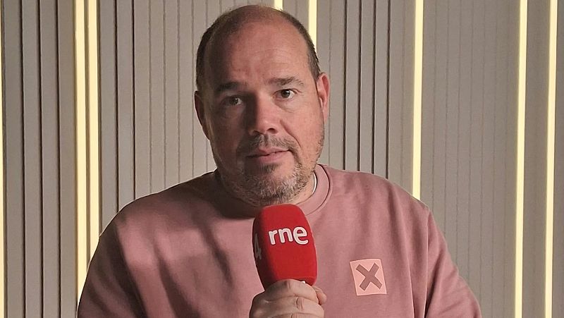 El periodista Marc Redorta viste sudadera salm�n y sujeta un micr�fono de R�dio 4 en un estudio con iluminaci�n c�lida.
