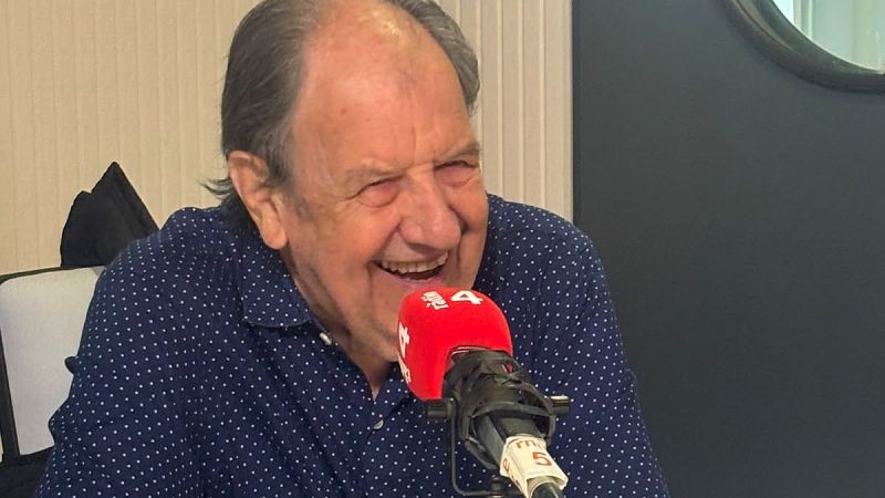 Plano medio del actor Josep Maria Pou sonriendo alegremente durante una entrevista en un estudio de radio ante un micr�fono con espuma roja.