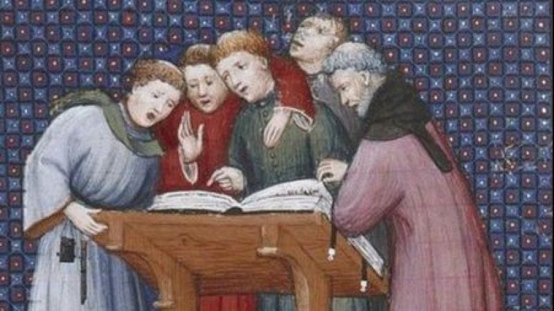 Cinco hombres con t�nicas medievales cantan congregados alrededor de un atril de madera con un gran libro de m�sica sacra sobre un fondo geom�trico ornamental.