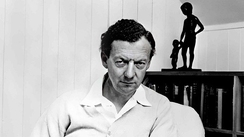 Retrato en blanco y negro del compositor Benjamin Britten, mirando fijamente a la c�mara en un entorno interior con libros y una peque�a escultura.