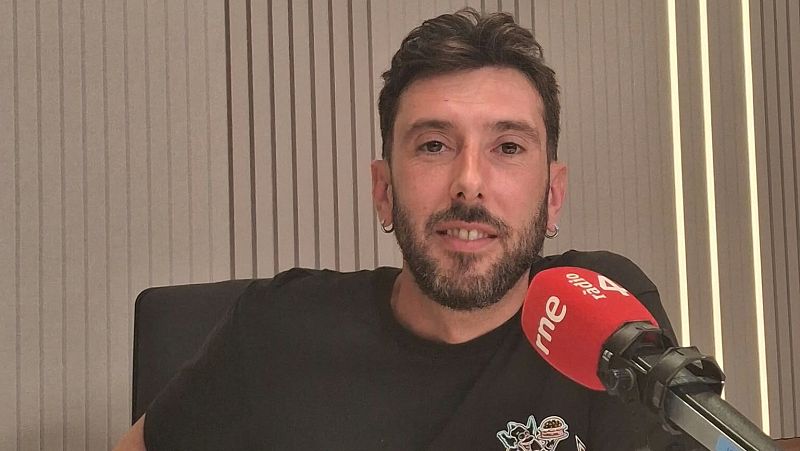 El periodista Marc Llibre sonr�e en el estudio de R�dio 4, con un micr�fono de espuma roja y logotipos en primer plano.