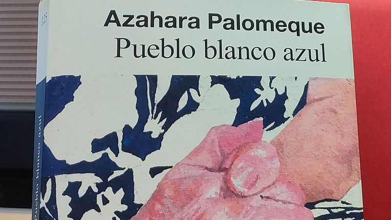 Primer plano de la portada del libro «Pueblo blanco azul» de Azahara Palomeque, con una ilustración de azulejos blancos y azules y detalles pictóricos rojizos de manos.