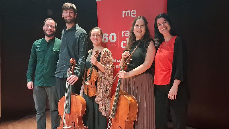 Cinco m�sicos posan sonrientes en un estudio de radio junto a un cartel rojo de RNE, sosteniendo instrumentos de cuerda barrocos.