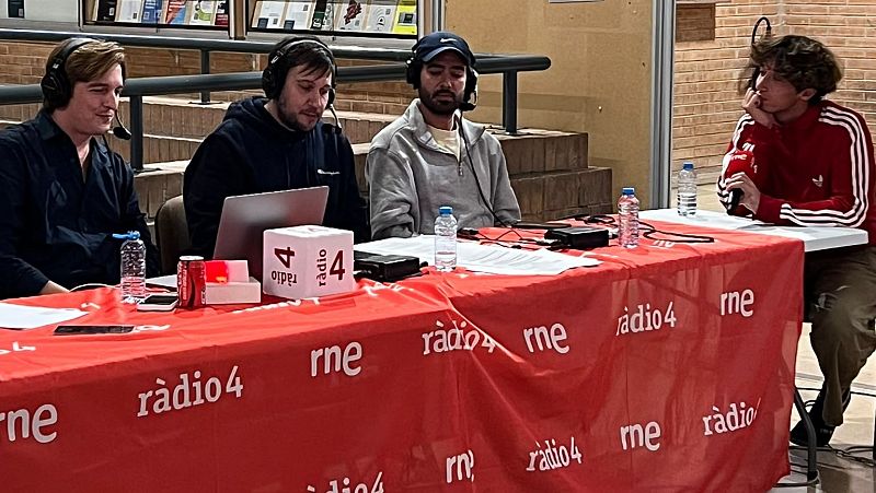 Cuatro personas participan en una retransmisi�n de radio sentadas ante una mesa roja con equipos t�cnicos, ordenadores y micr�fonos en un espacio interior.