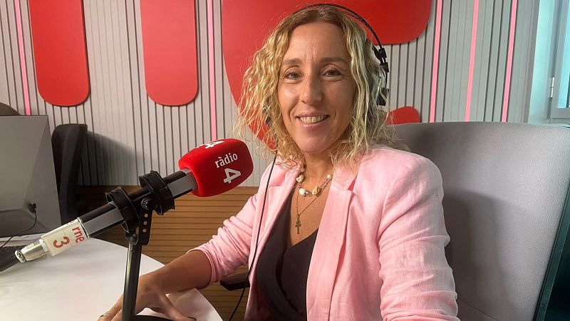 Mujer rubia sonriendo con auriculares y americana rosa en un estudio de radio ante un micr�fono con la marca R�dio 4.