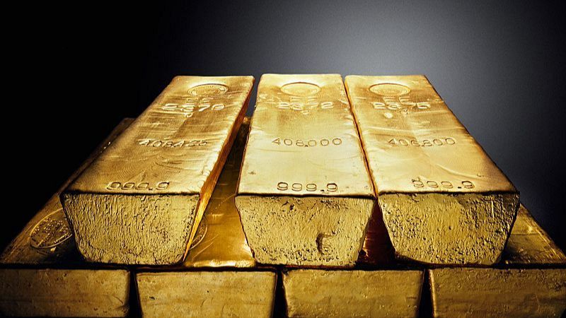 Primer plano de lingotes de oro macizo apilados con superficies doradas, brillantes e inscripciones grabadas que indican su pureza de 999.9.